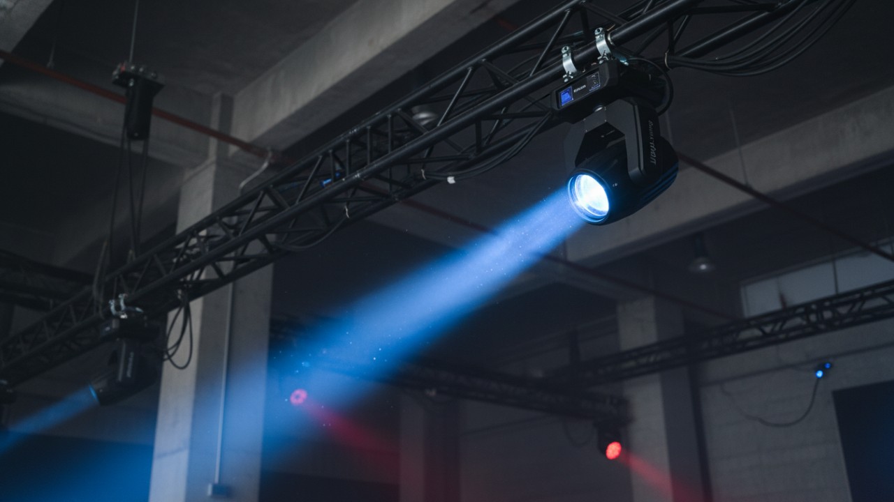 A professional Uplus Lighting beam moving head fixture projecting a sharp blue light beam on a stage.